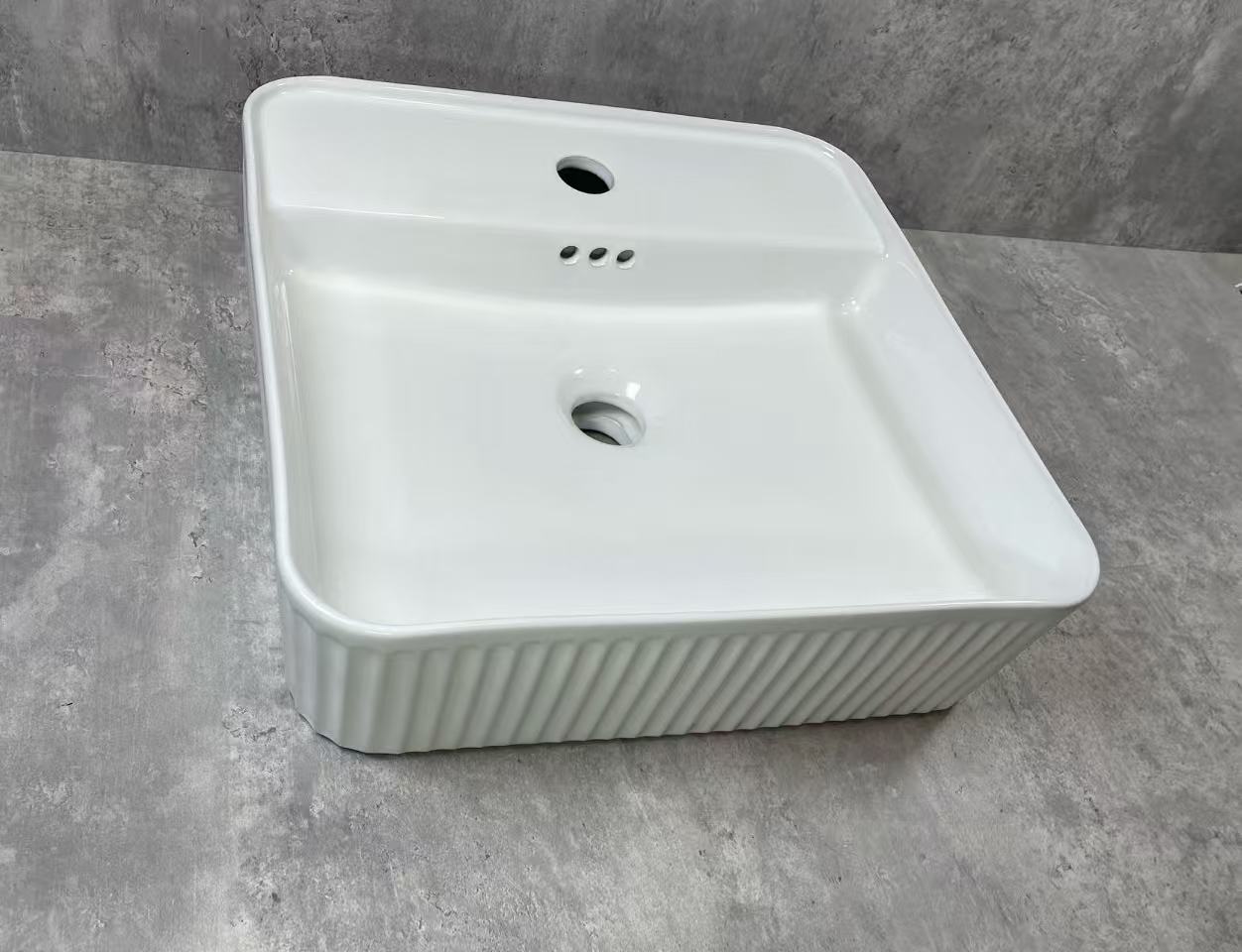 White ceramic sink on a gray concrete floor
