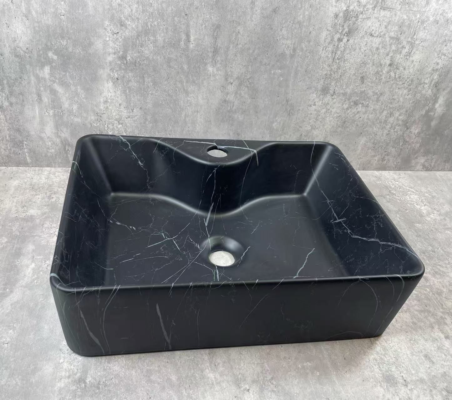 Black marble sink on a gray concrete background